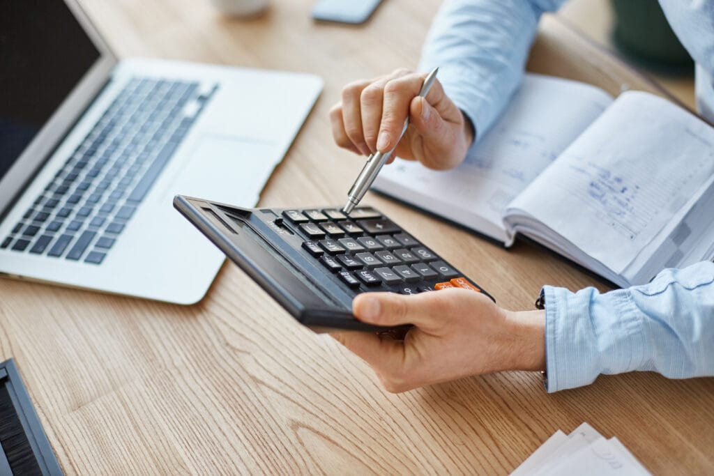 cropped view professional serious finance manager holding calculator hands checking company month s profits